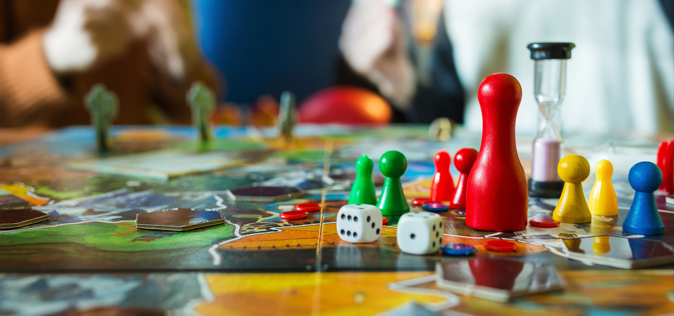 Peças de jogo de tabuleiro coloridas, incluindo peões vermelhos, verdes, amarelos e azuis, com dados.