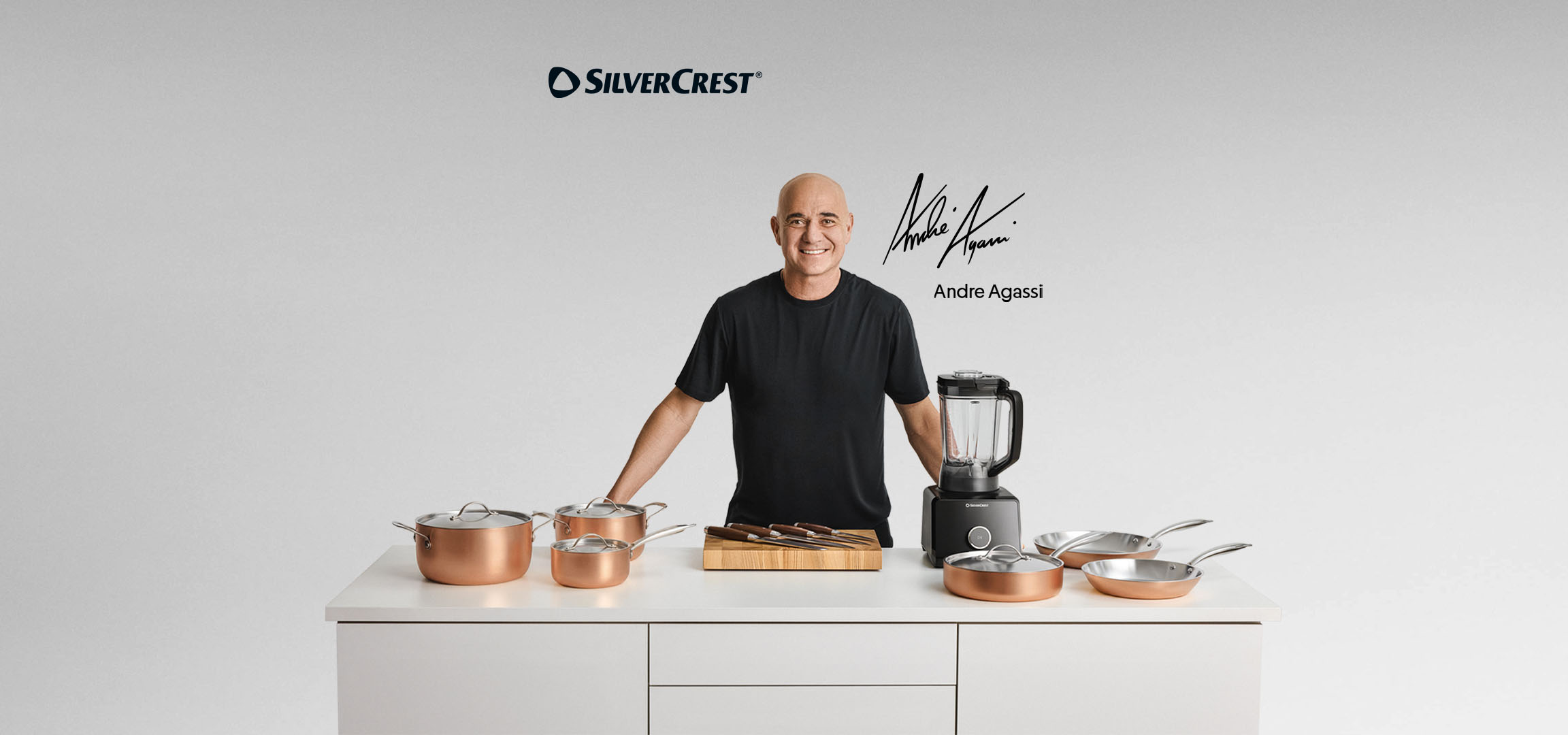 Andre Agassi com um conjunto de panelas cor de cobre, uma liquidificadora e um bloco de facas.