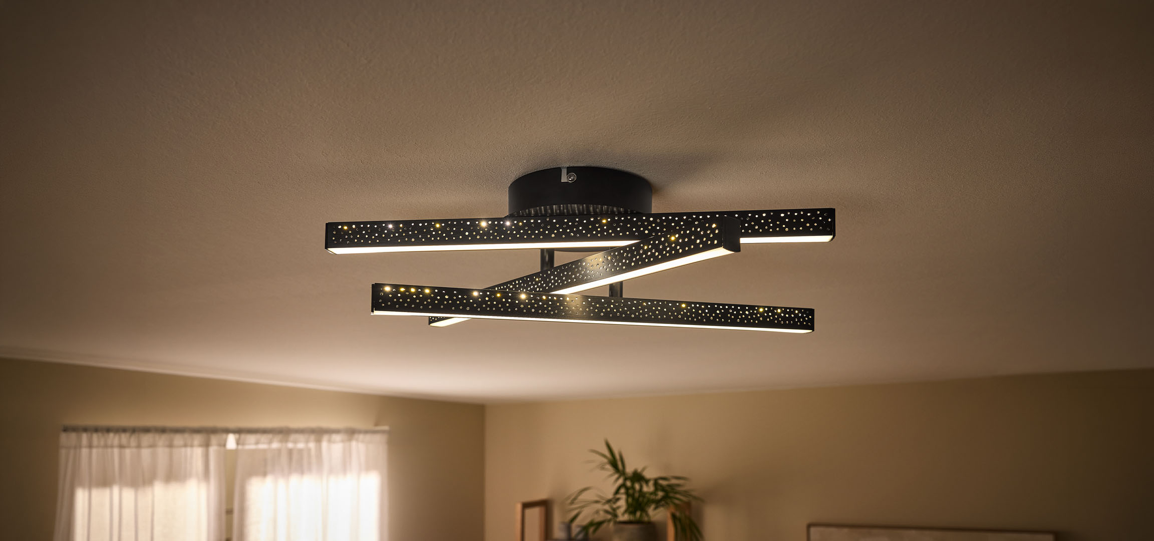 Candeeiro de teto LED moderno com barras pretas perfuradas e luz quente.