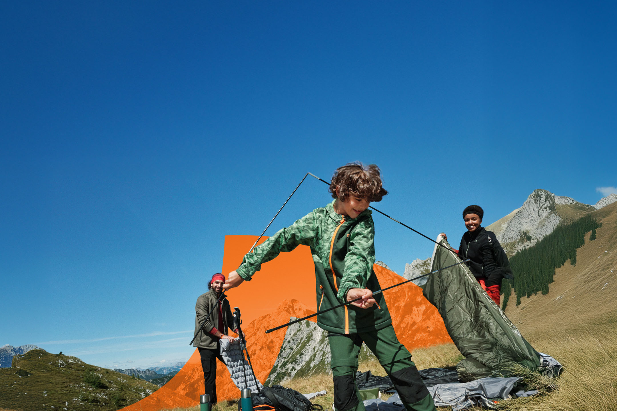 Família a montar uma tenda nas montanhas, com equipamento de campismo e roupa de exterior.