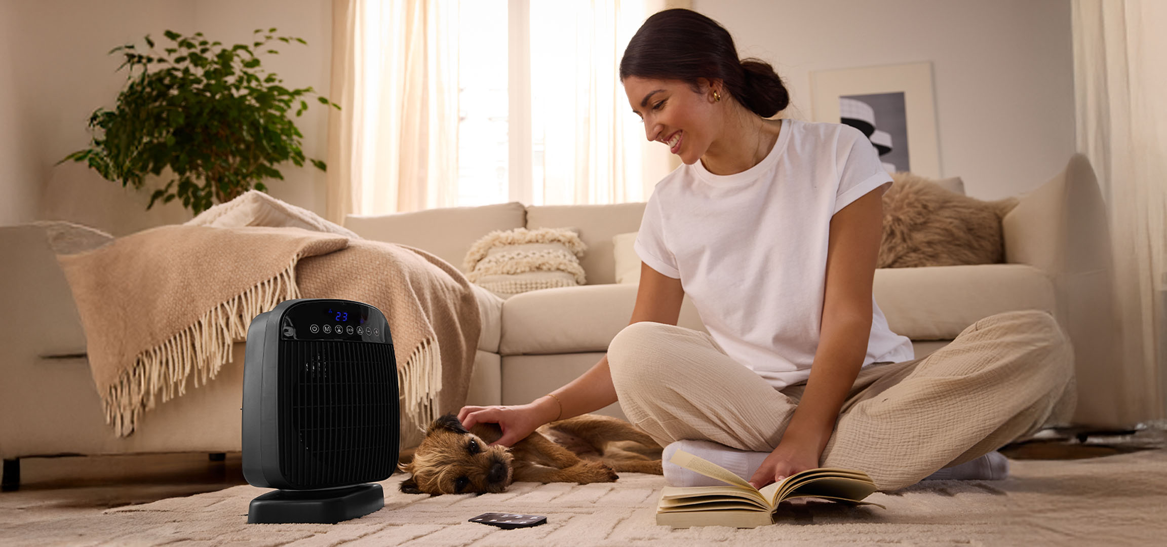Uma mulher brinca com um cachorro ao lado de um aquecedor elétrico na sala de estar.