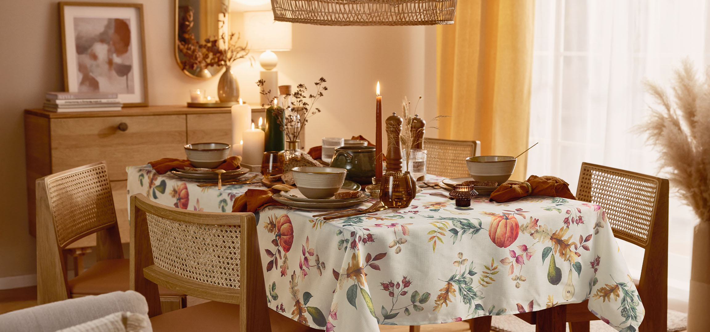 Sala de jantar com mesa posta para refeição, com toalha floral e iluminação acolhedora.