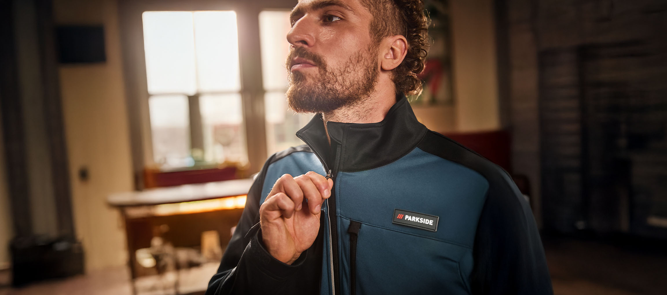 Homem com casaco de trabalho Parkside azul e preto a apertá-lo