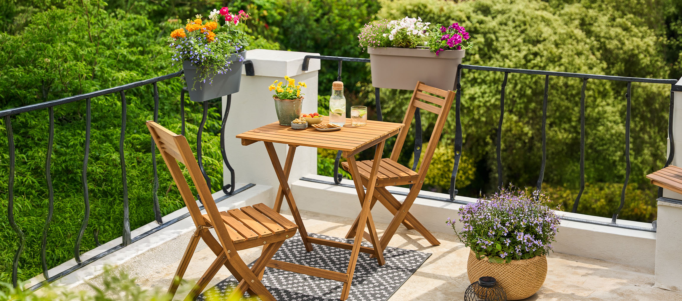 Conjunto de mobiliário de varanda com mesa e cadeiras dobráveis, decorado com vasos de flores.