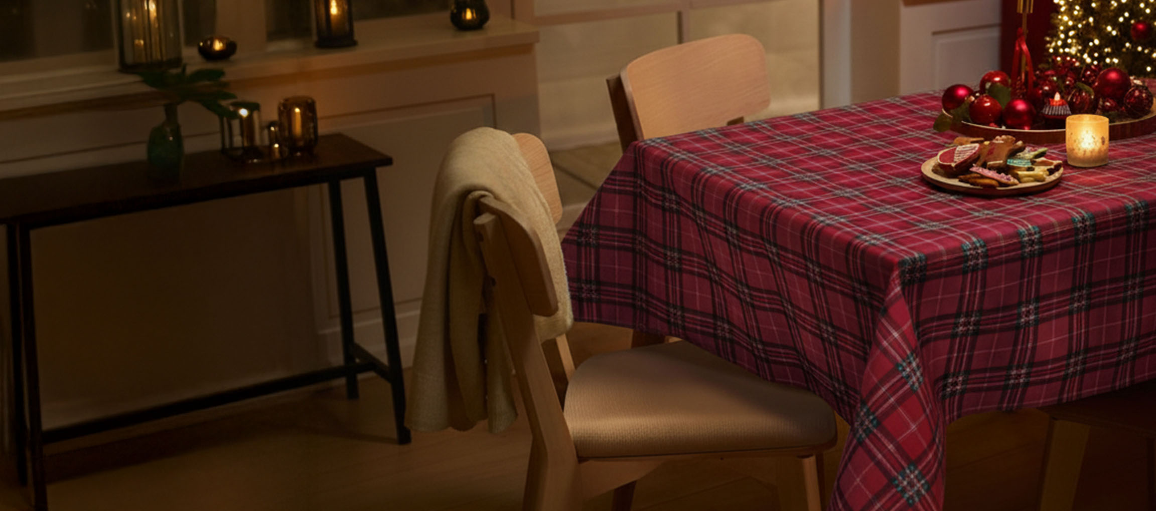 Mesa de Natal com toalha xadrez vermelha, cadeiras e biscoitos de Natal.