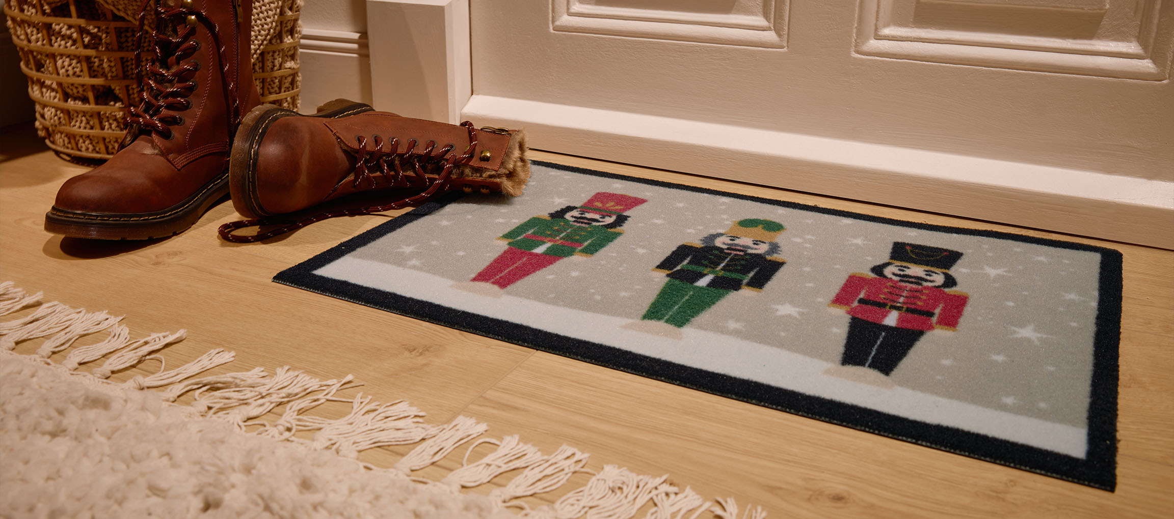 Capacho de Natal com quebra-nozes, botas castanhas e cesto de vime à entrada.