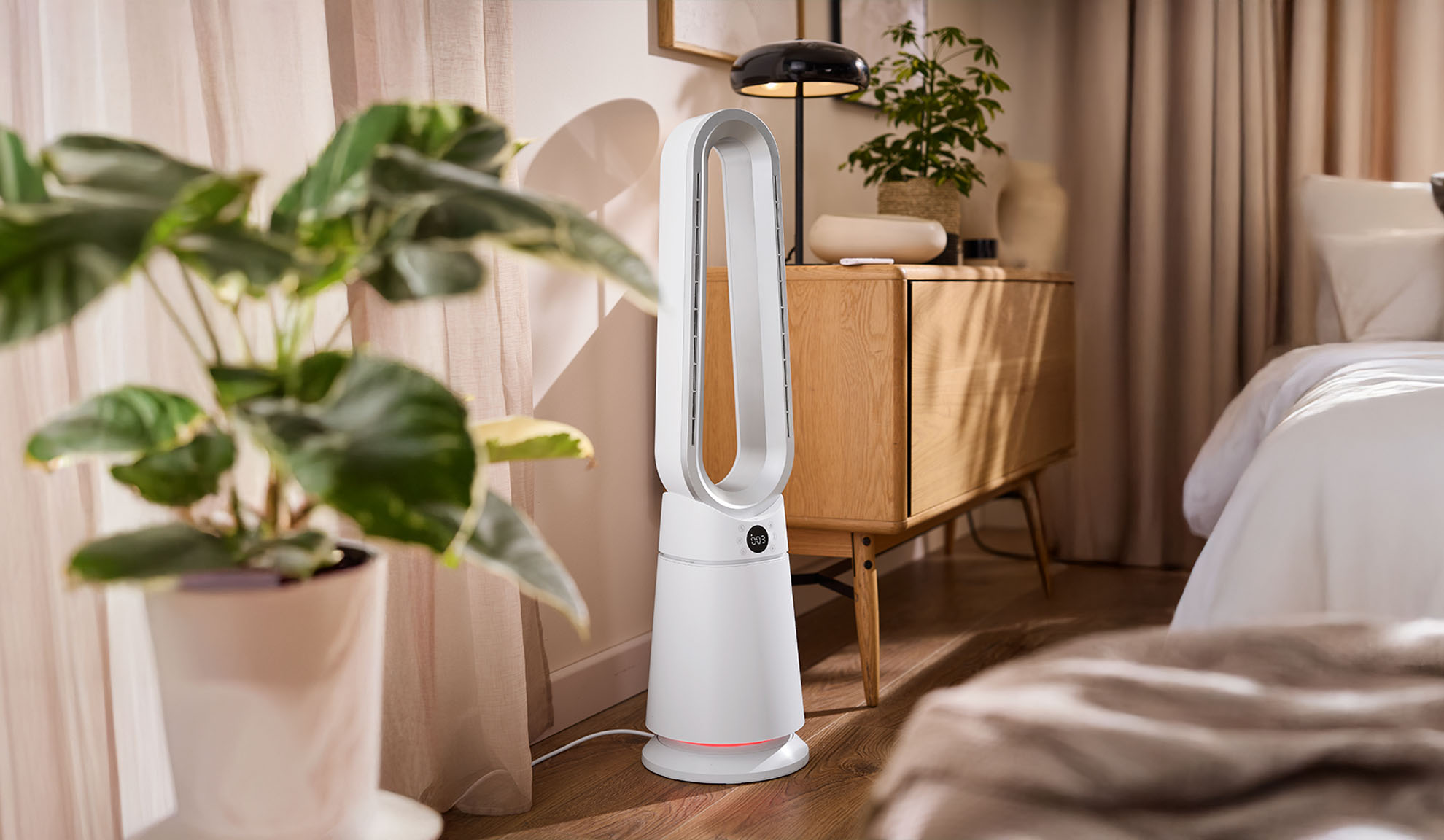 Ventoinha de torre branca num quarto moderno com plantas e móveis de madeira.