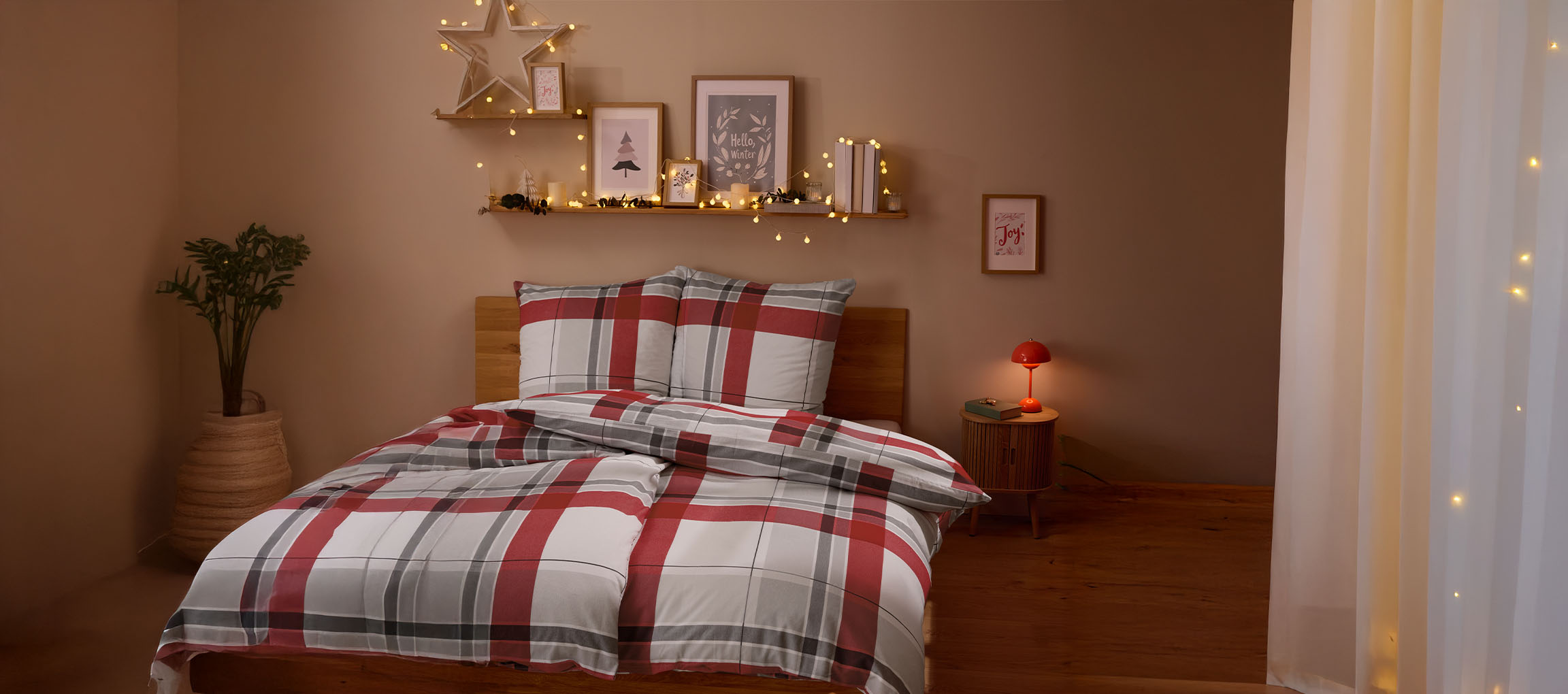 Quarto acolhedor com roupa de cama xadrez vermelha e cinzenta, decorações de Natal e luzes.