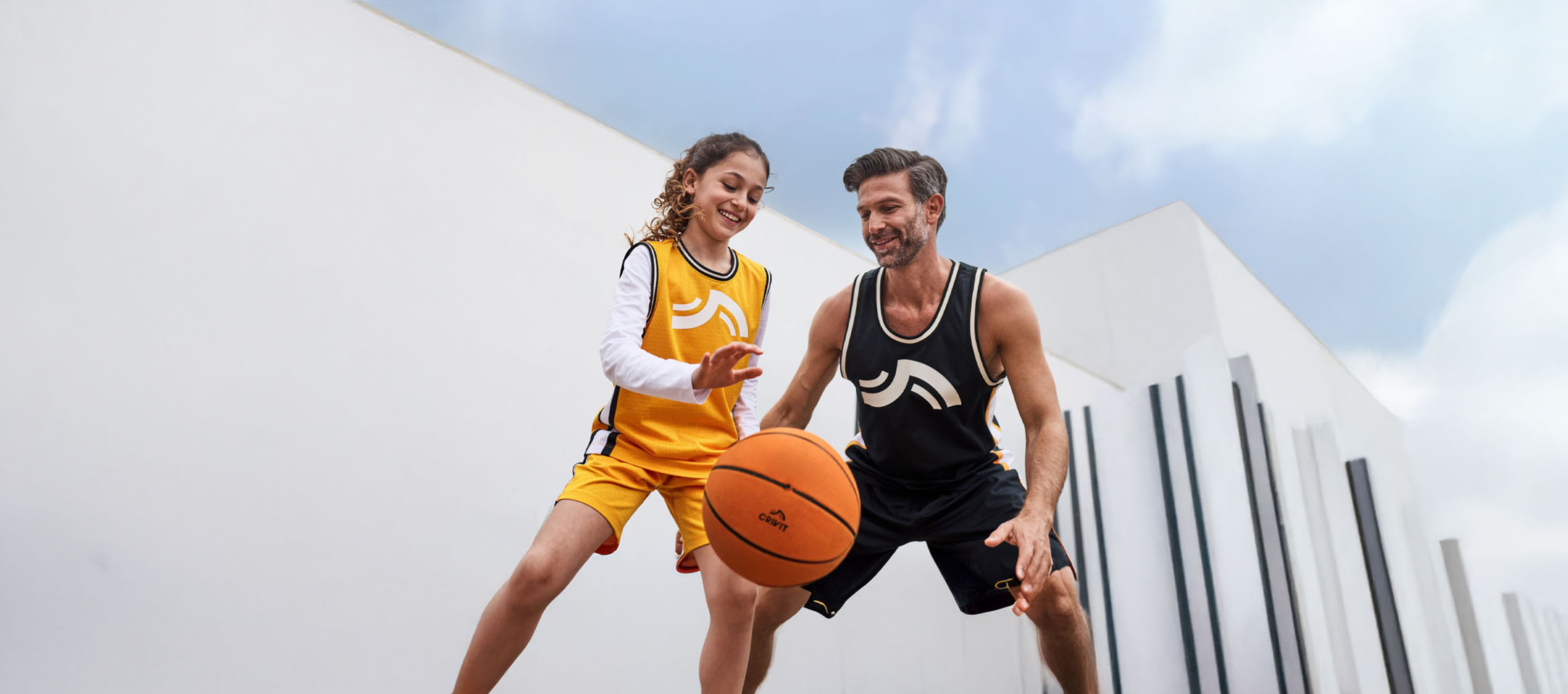 Pai e filha a jogar basquetebol com equipamento de basquetebol e bola