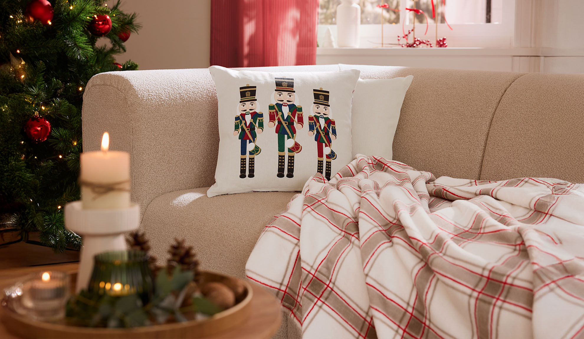 Sala de estar de Natal com sofá, almofadas de quebra-nozes, manta xadrez e velas.