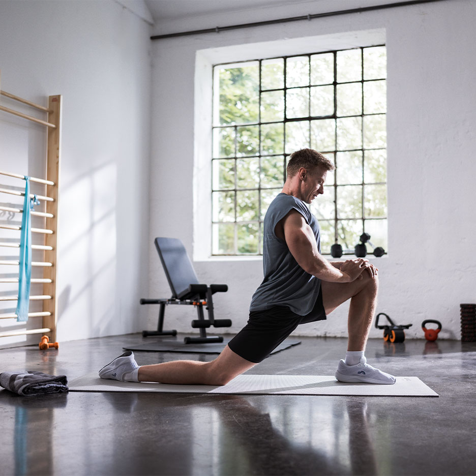 Homem alongando-se em um tapete de yoga na academia.