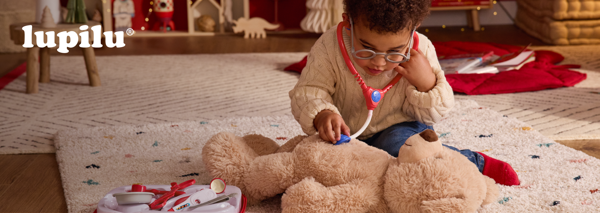 Criança a brincar ao médico com um ursinho de peluche e um kit de médico Lupilu.