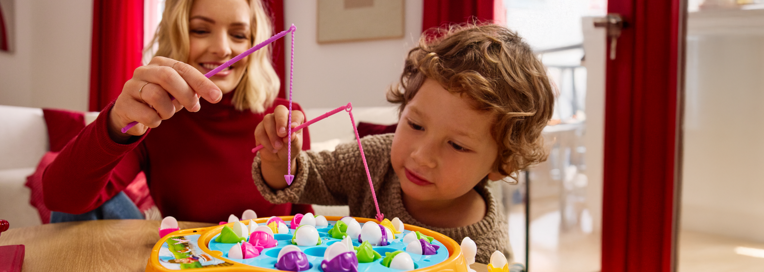 Mãe e filho a jogar um jogo de pesca com brinquedos coloridos.