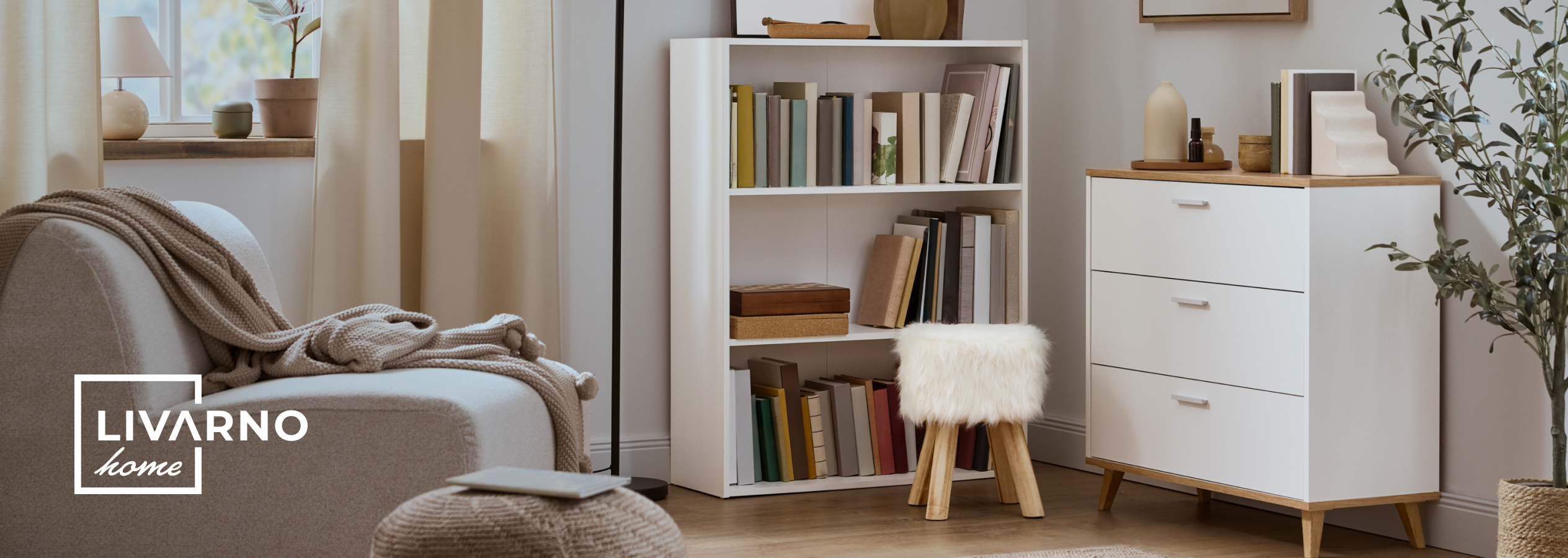 Sala de estar acolhedora com estante branca, cómoda e poltrona com manta.