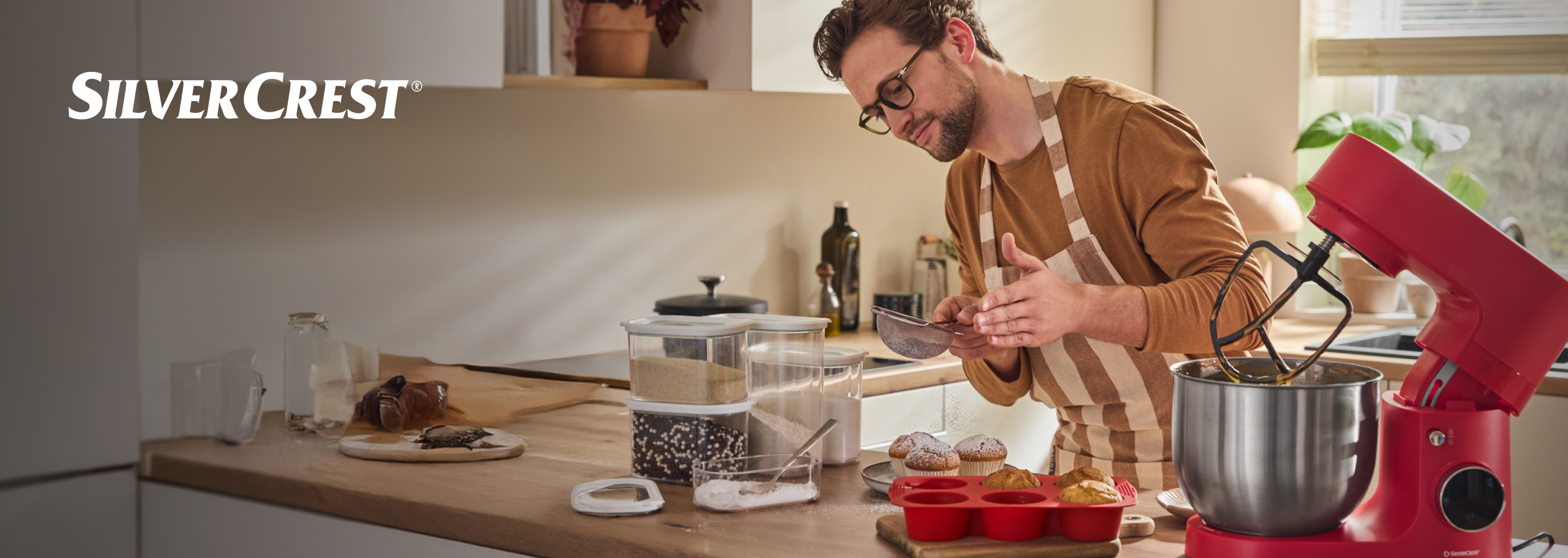 Homem a peneirar ingredientes para cozinhar com uma batedeira SilverCrest vermelha.
