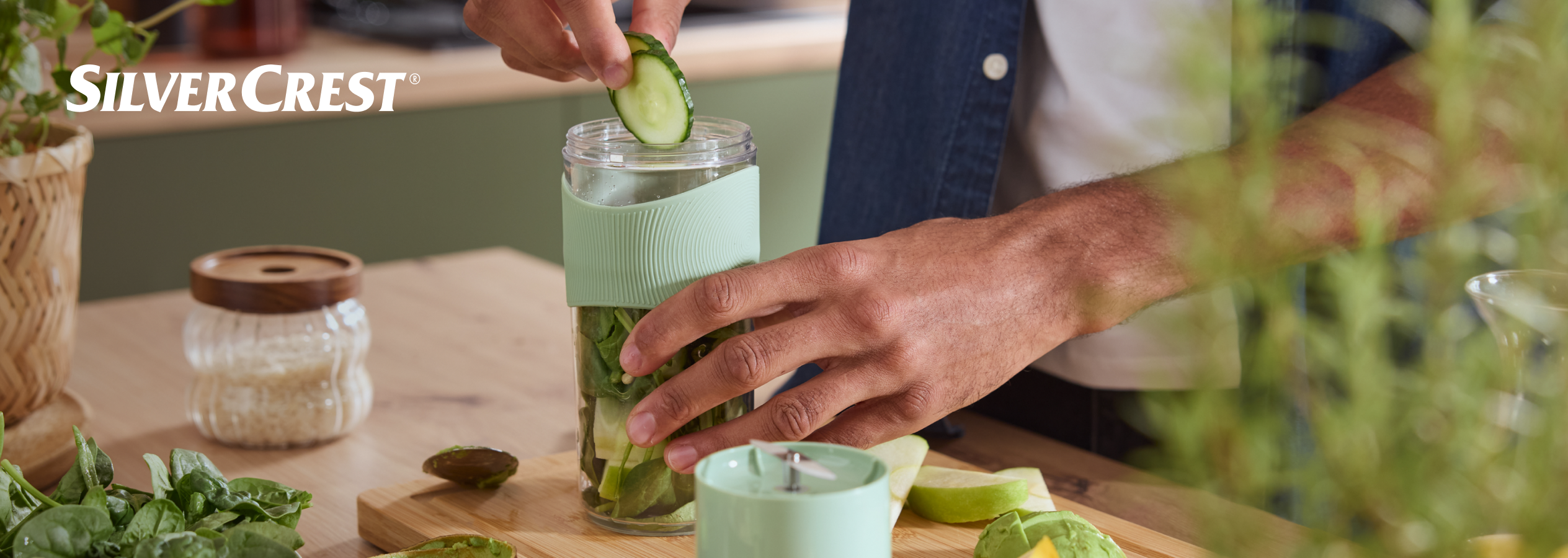 Homem a preparar um batido verde com um liquidificador portátil SilverCrest.