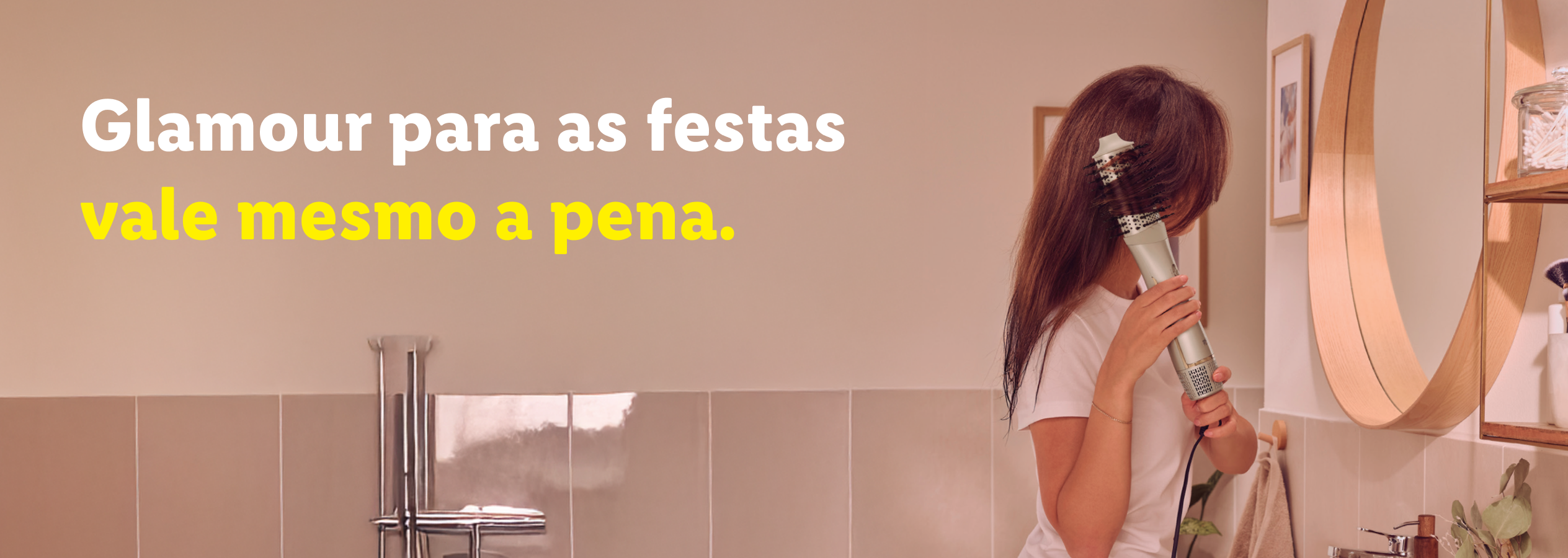 Mulher a secar o cabelo com uma escova secadora. Texto: 'Glamour para as festas vale mesmo a pena.'