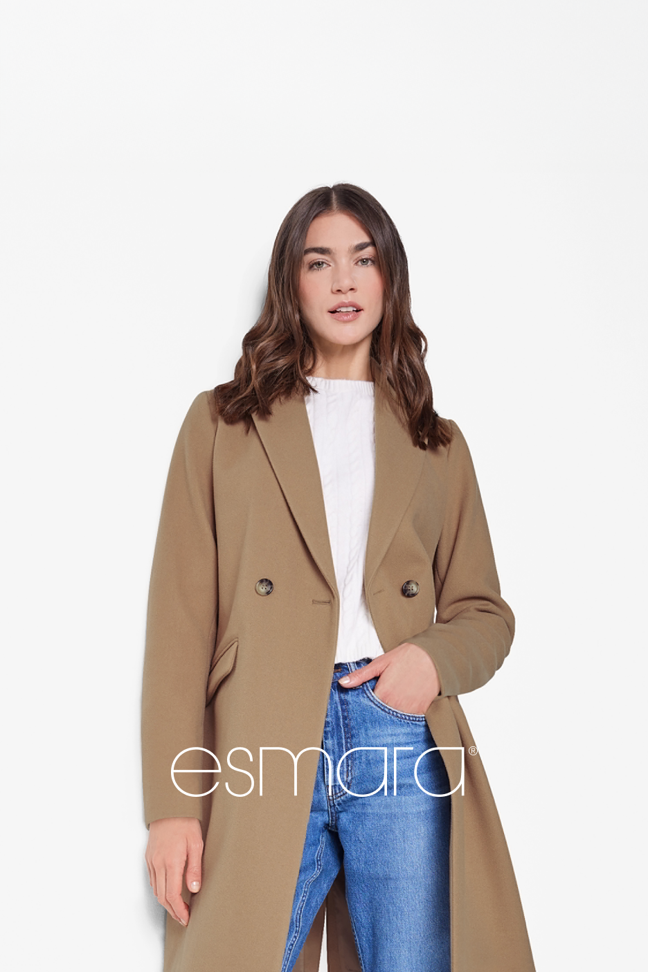 Mulher com casaco camel Esmara, camisola branca e jeans azuis.