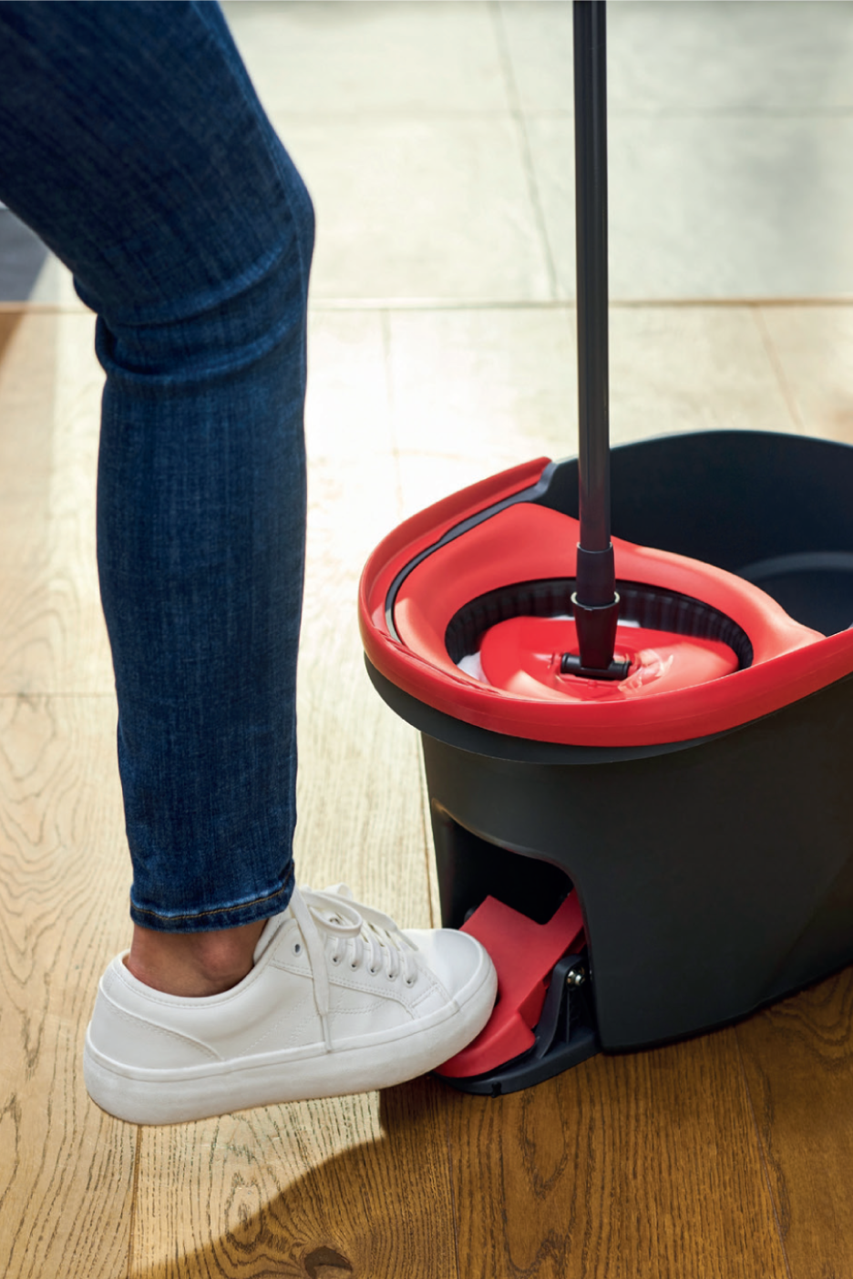Pessoa a usar um balde de esfregona com pedal e esfregona.