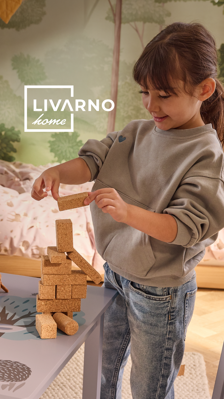Menina a construir uma torre com blocos de cortiça, com o logótipo LIVARNO home.