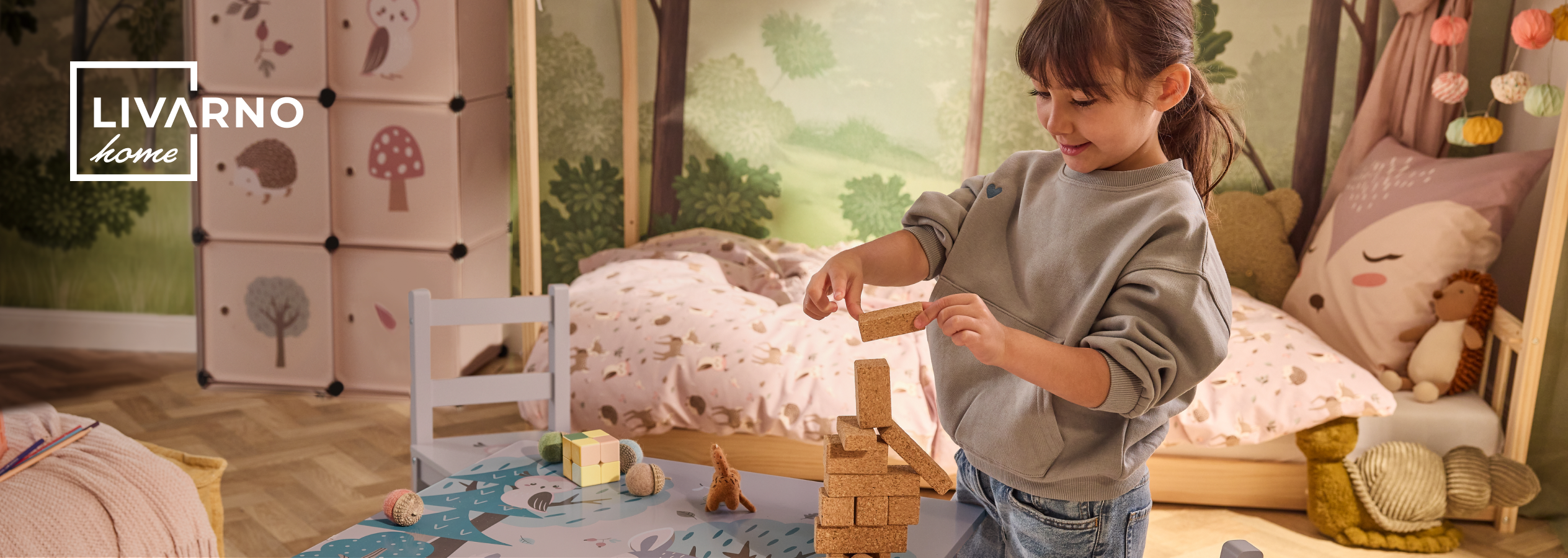 Criança a brincar com blocos de construção numa sala com arrumação e cama LIVARNO home.