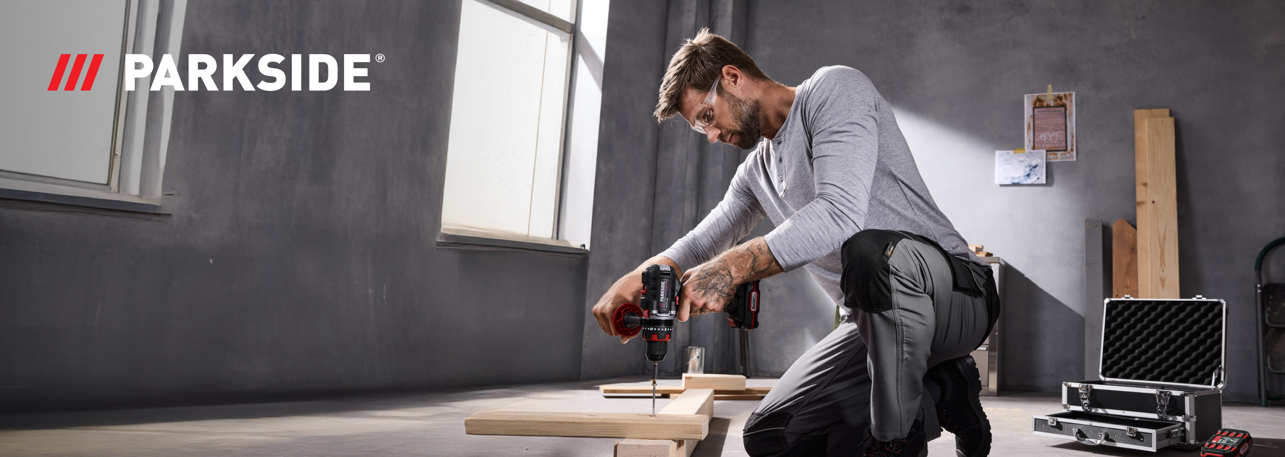 Homem a usar uma berbequim-aparafusadora PARKSIDE para aparafusar madeira.