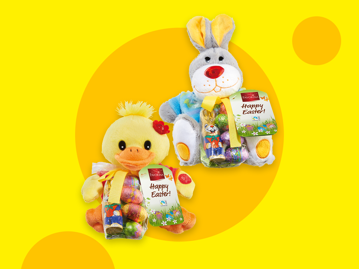 Dois peluches de Páscoa, um pato e um coelho, cada um com um saco de ovos de chocolate e um coelhinho de chocolate, com a mensagem 'Happy Easter!'.