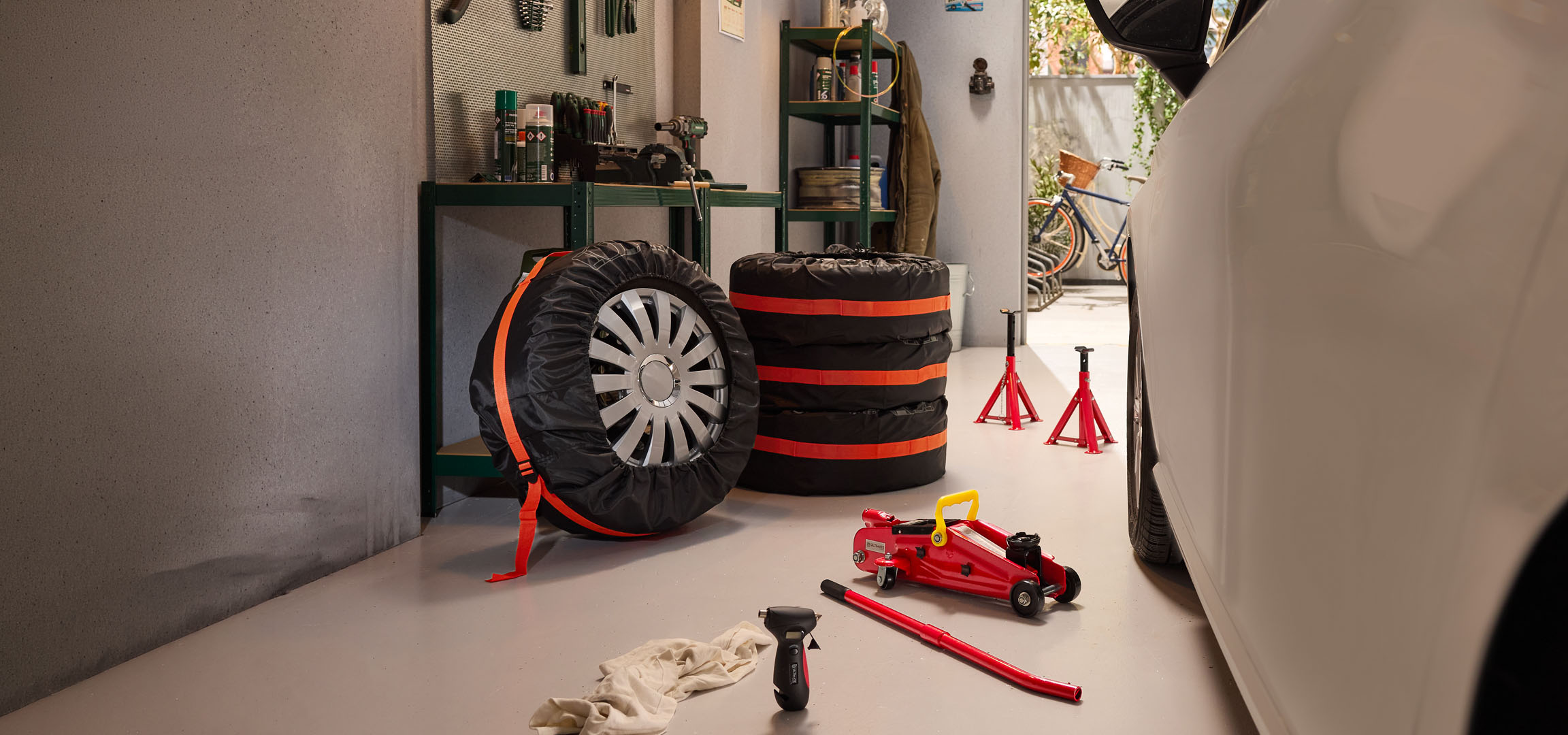 Pneus de inverno guardados numa garagem com um macaco hidráulico e cavaletes.