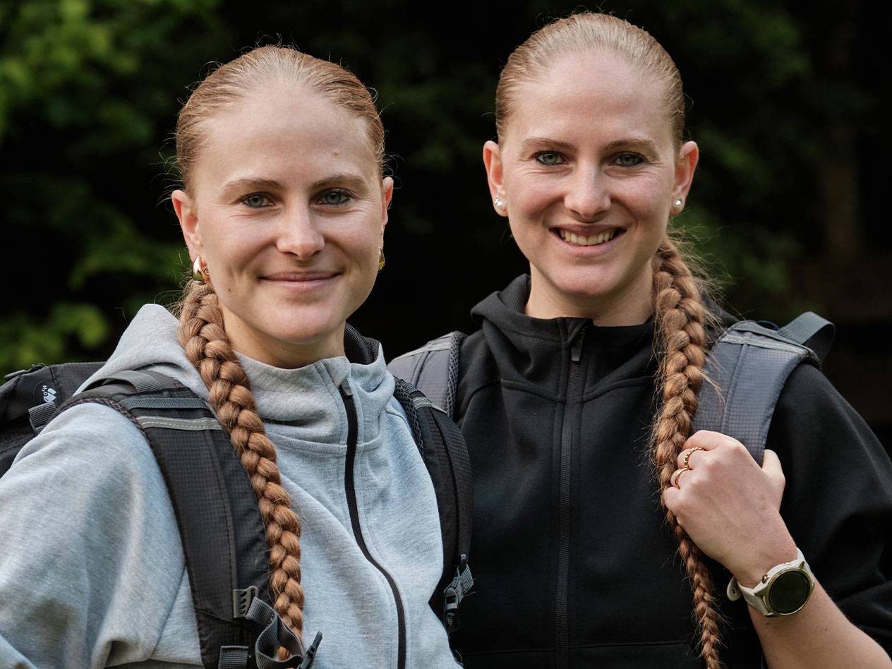 Duas mulheres com mochilas estão juntas.